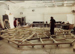 Image of a clean scene shop with empty white walls and a big structure on the floor being built by two people